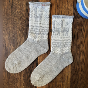 Pair of gray socks with white pattern on a wooden surface
