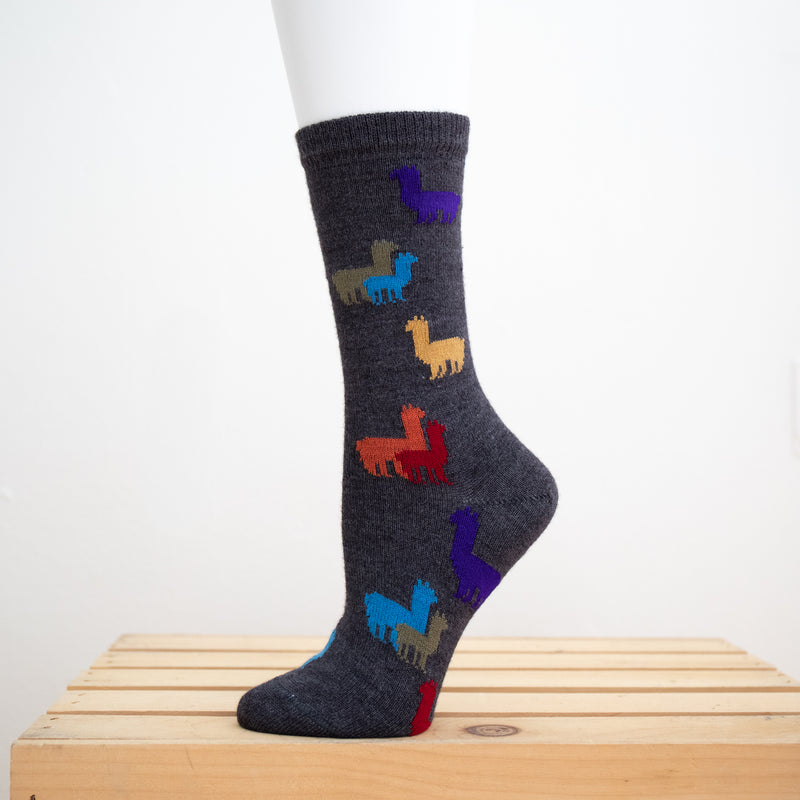 Children's Rainbow Alpaca Herd Socks. Charcoal socks with rainbow alpacas on them in front of a white background.