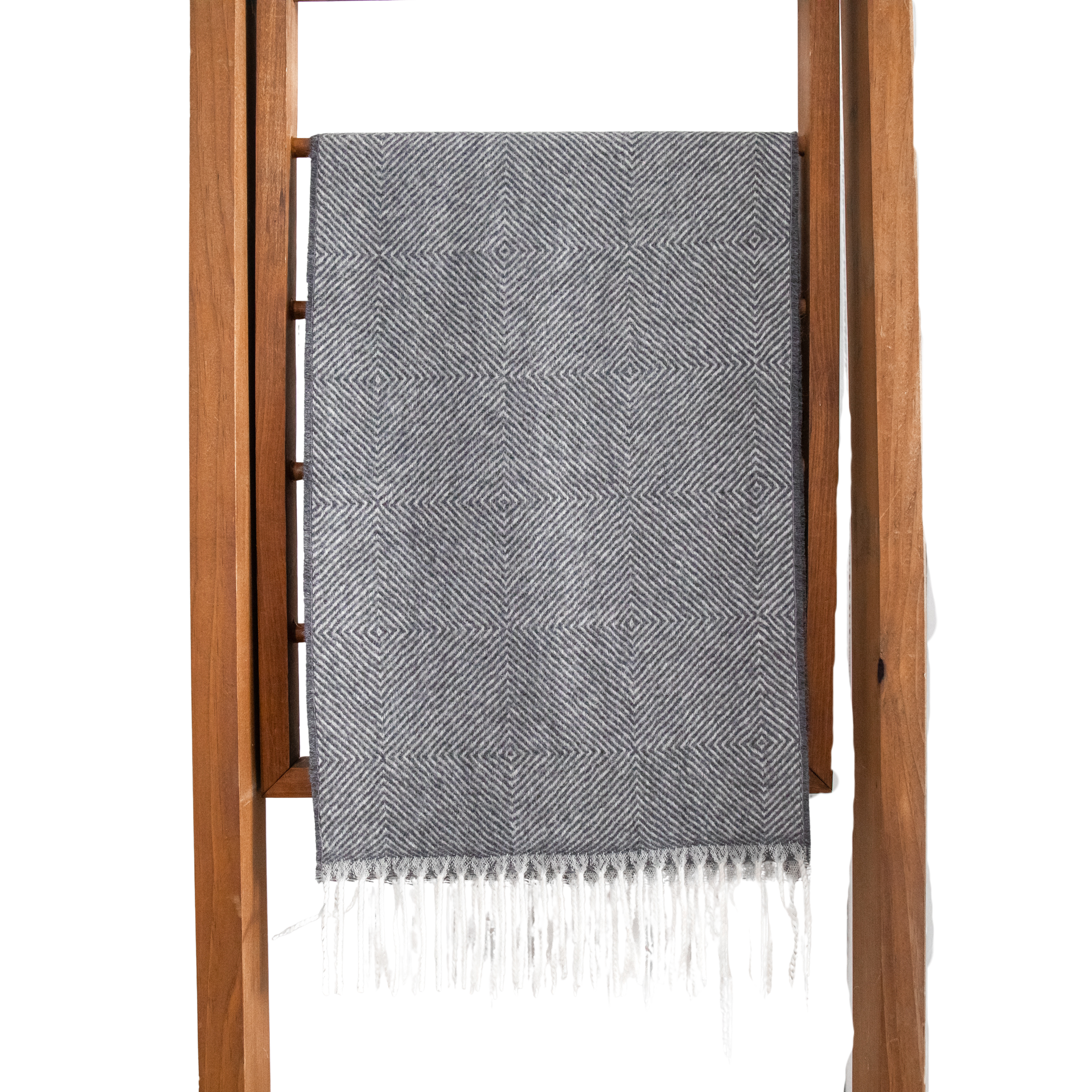 Gray patterned scarf with white fringe draped over a wooden ladder on a white background