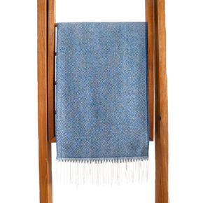 Blue patterned towel with white fringe draped over a wooden rack on a white background