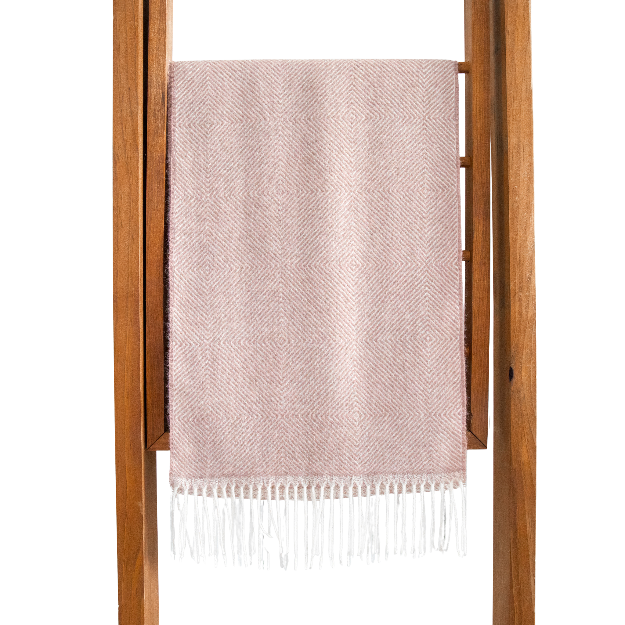 Pink woven blanket with white fringe on a wooden rack against a white background