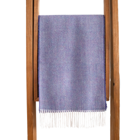 Purple woven blanket with white fringe draped over a wooden frame on a white background