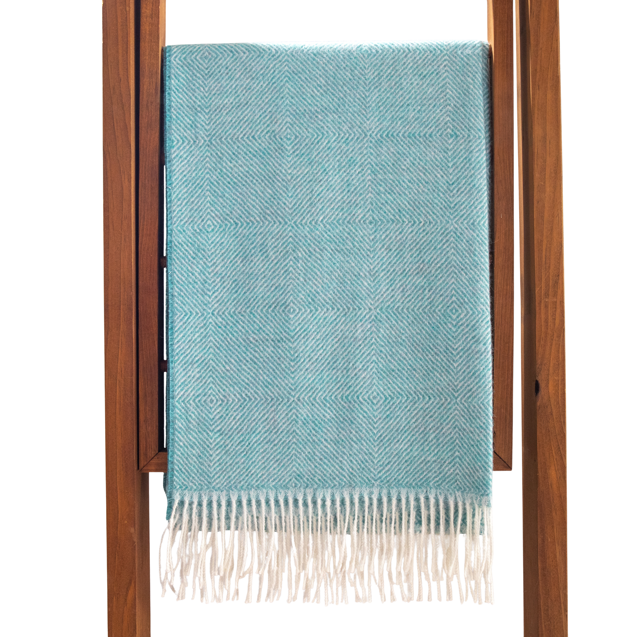 Teal blanket with white fringe draped over a wooden ladder on a white background