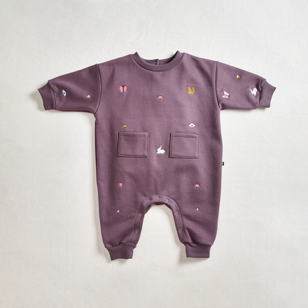 Oeuf Embroidered Terry Romper - purple romper with front pockets and misc embroidery on a neutral background