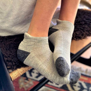 Person wearing gray socks with dark toes on a blurred indoor background