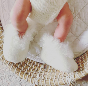 Close-up of a baby's feet in white fluffy socks on a textured surface