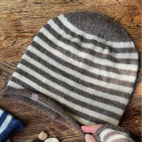Striped knitted hat on a wooden surface with a hand holding it