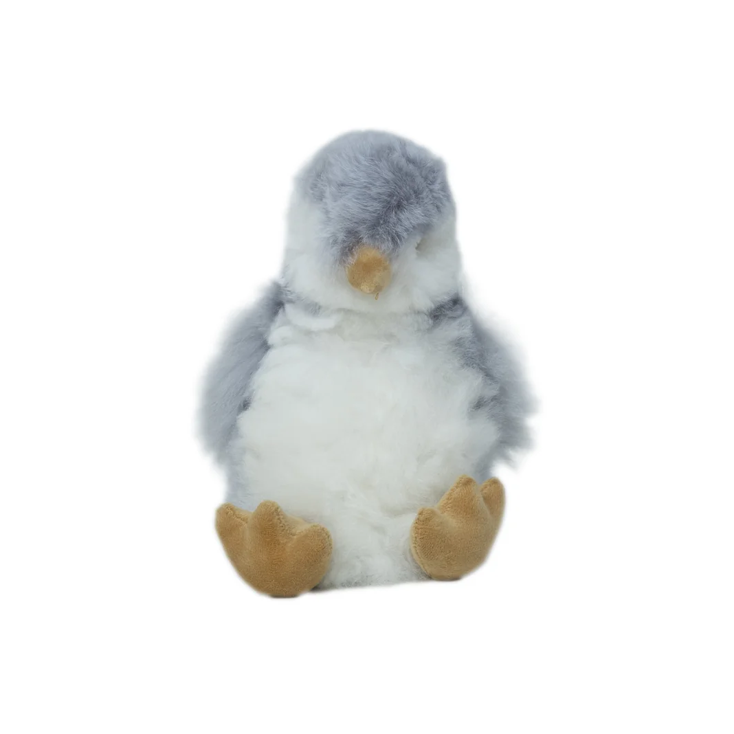 A small plush penguin toy with gray and white fur, a yellow beak, and yellow feet, centered on a plain white background.