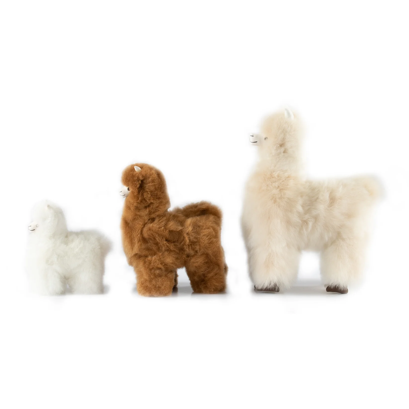 Three fluffy alpaca plush toys in white, medium brown, and fawn, arranged side by side on a plain white background.
