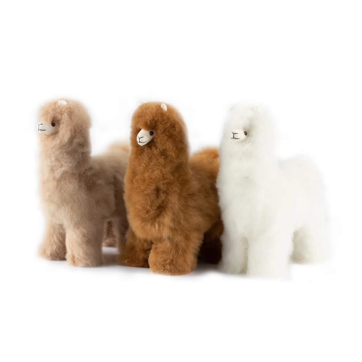 Three fluffy alpaca plush toys in light beige, medium brown, and white, standing side by side on a plain white background.