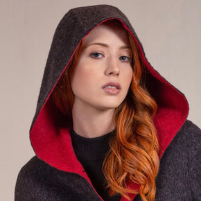 Kuna Anastasia Reversible Coat - model wearing black coat with red lining, toggle buttons, hood, and front pockets