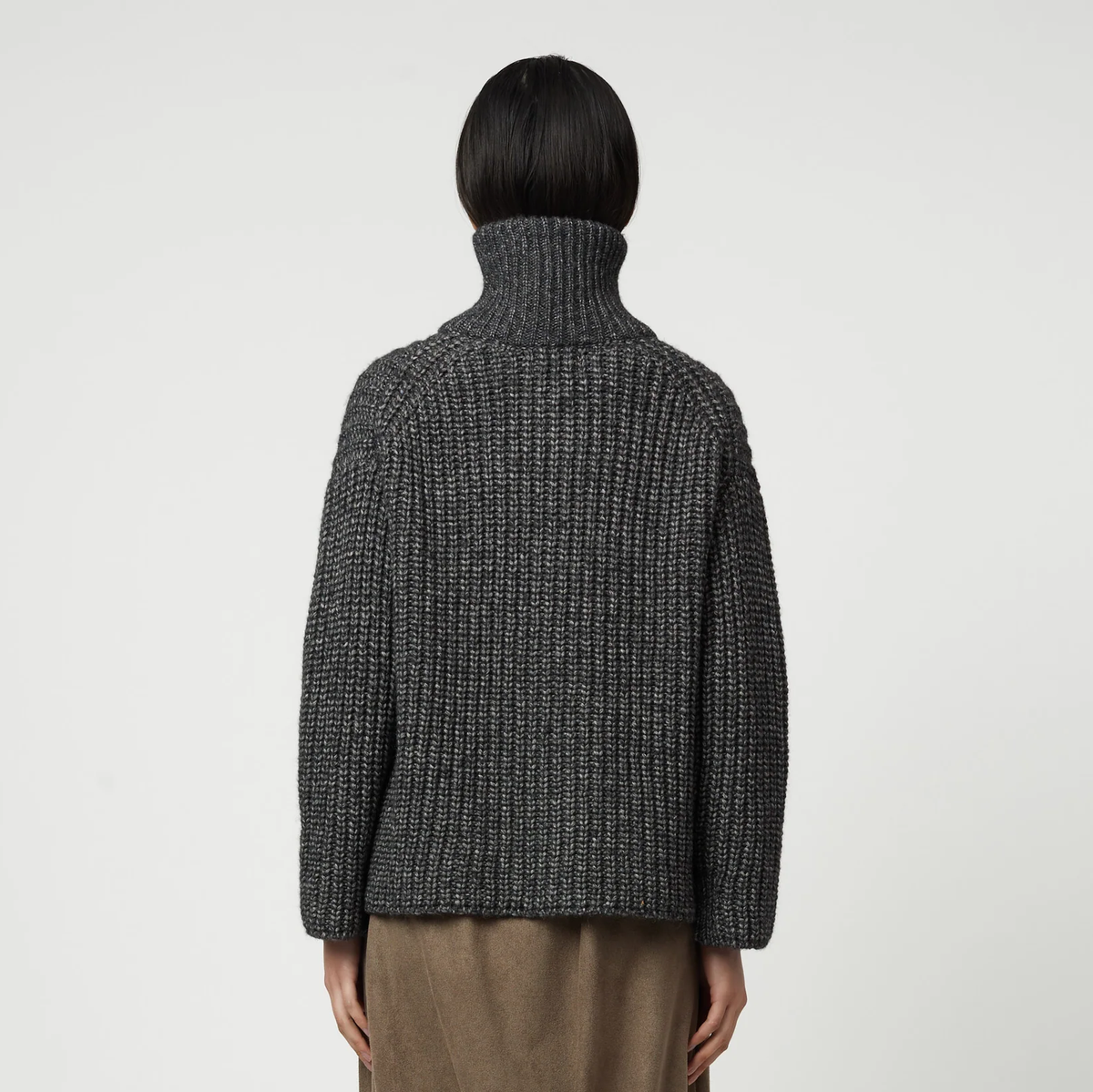 Woman wearing a charcoal grey ribbed knit zip-up turtleneck cardigan.