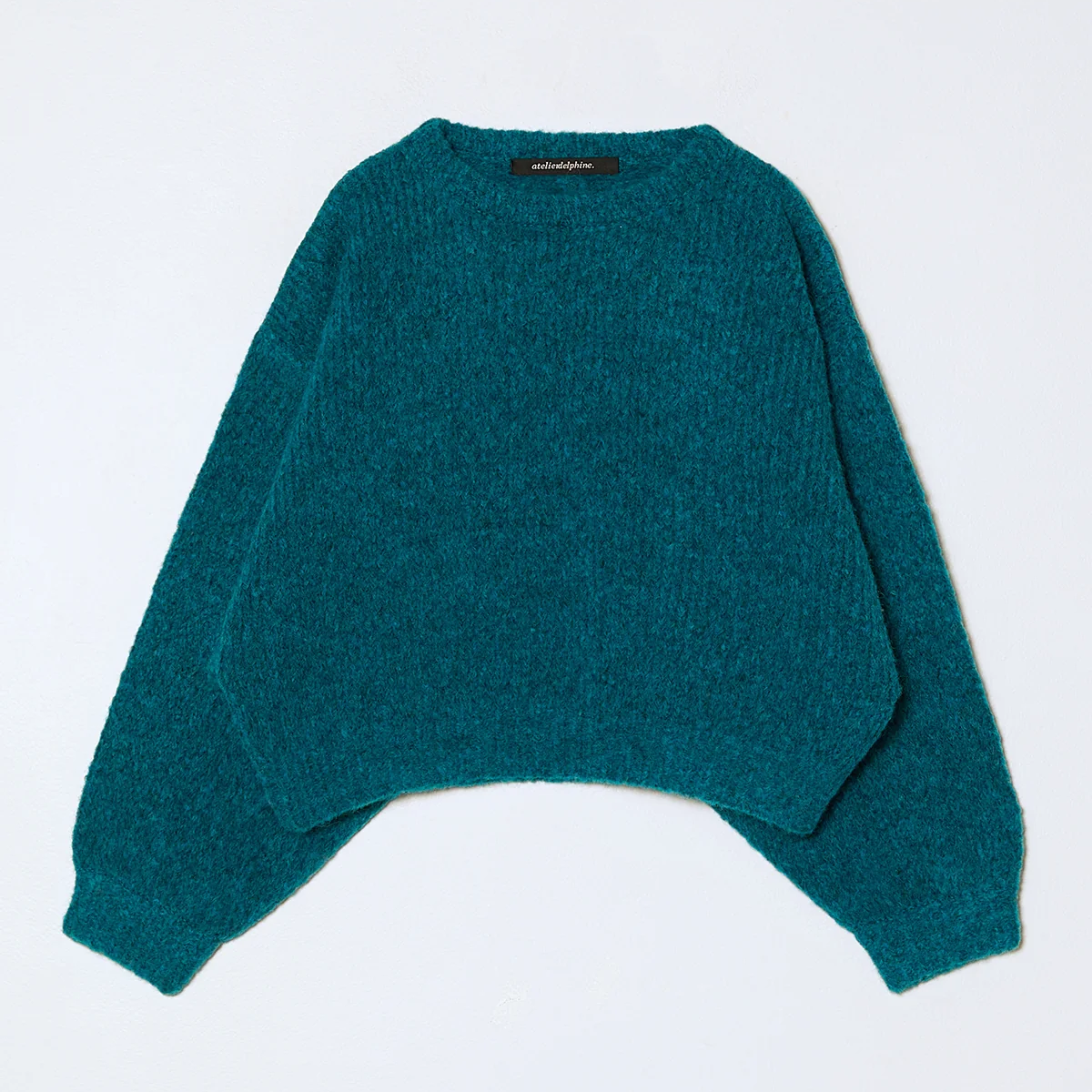 Knit cropped balloon sleeve sweater in teal on a neutral background.