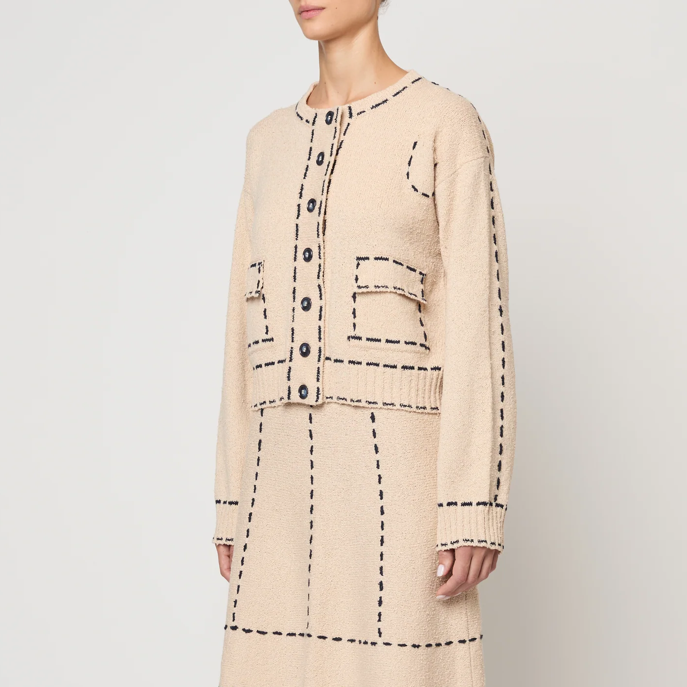 Beige two-piece with navy line details worn by a person on a white background