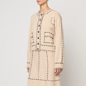 Beige two-piece with navy line details worn by a person on a white background