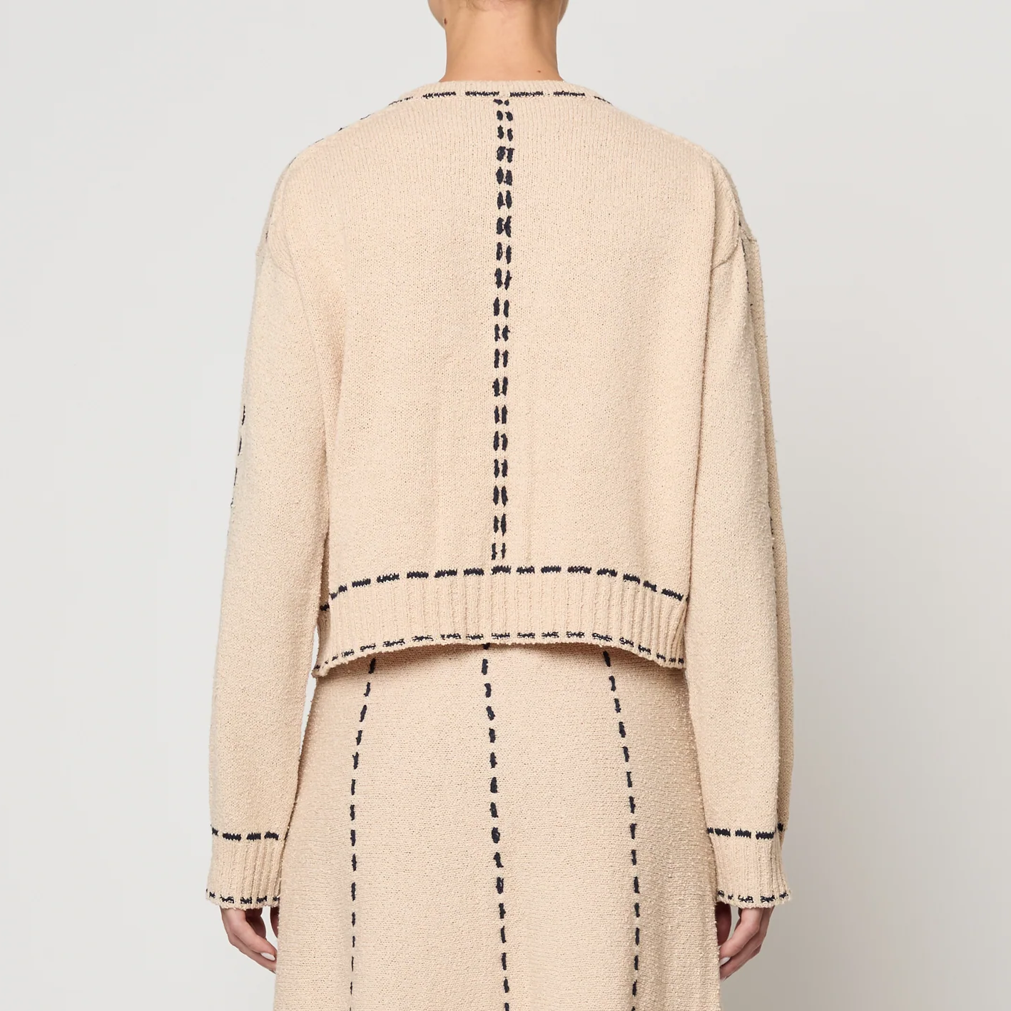 Beige two-piece suit with navy detailing on a white background