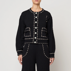 Person wearing a black outfit with tan stitching on a white background