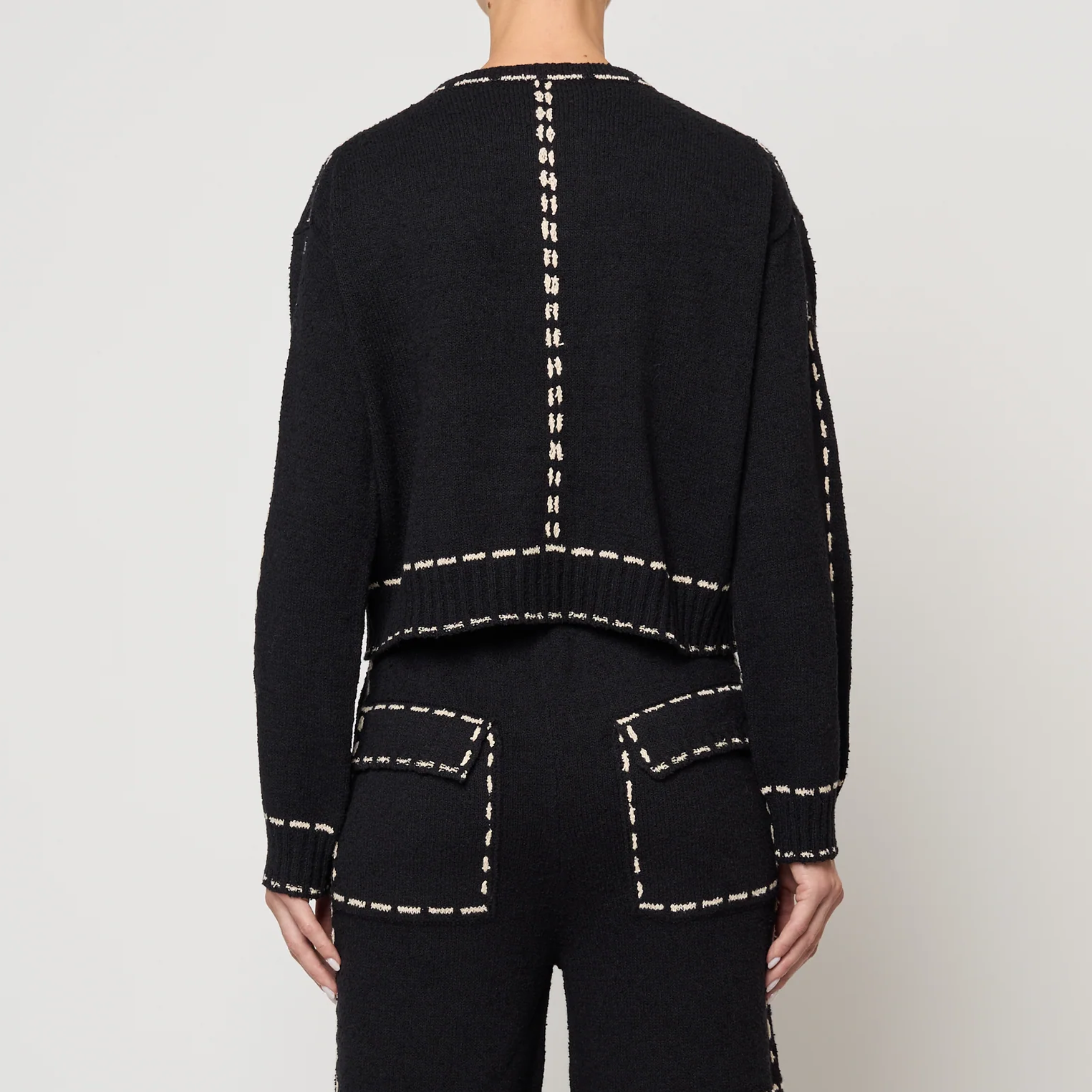 Black outfit with tan stitching on a plain background