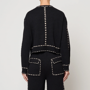 Black outfit with tan stitching on a plain background
