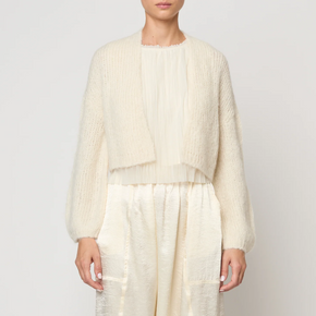 Person wearing a cream-colored outfit with a jacket and pants on a white background