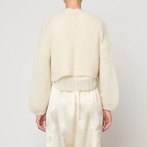 Person wearing a cream-colored outfit against a white background
