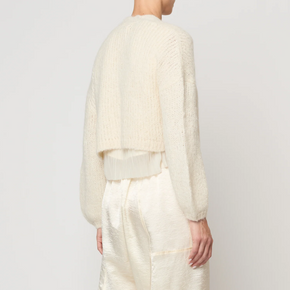 Person wearing a cream-colored outfit against a white background
