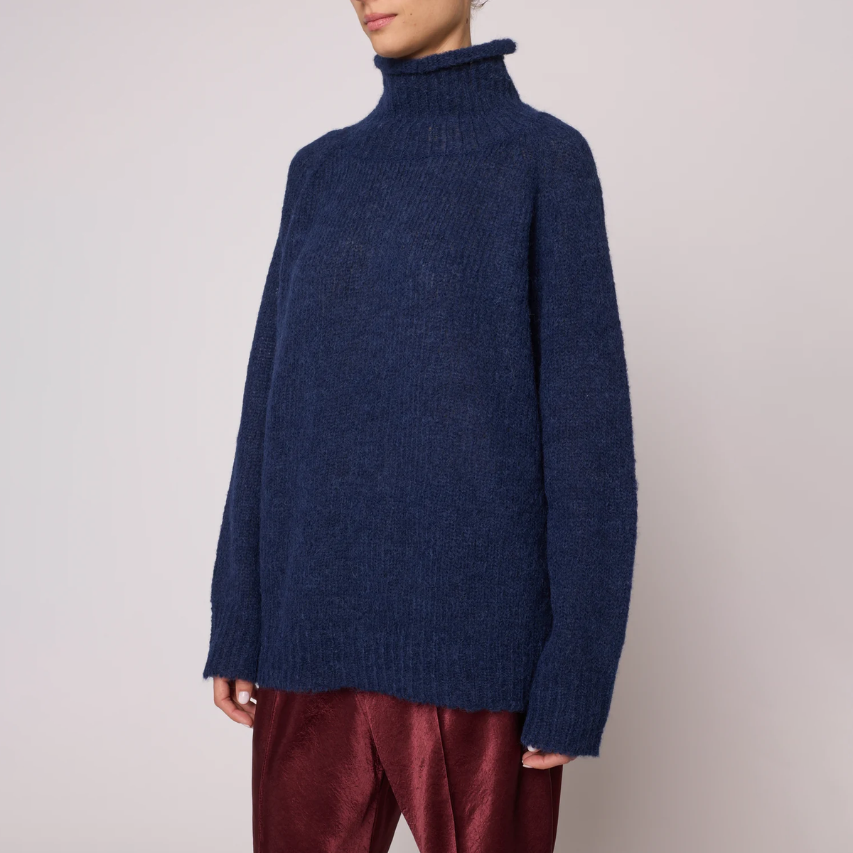 A woman wearing a navy blue knit turtleneck sweater.