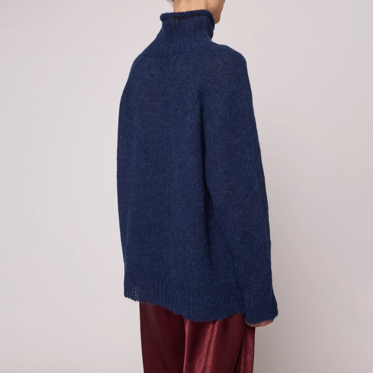 A woman wearing a navy blue knit turtleneck sweater.
