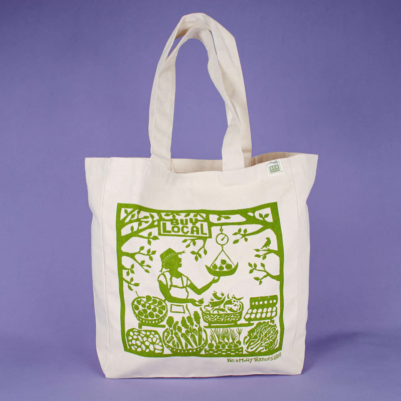 White tote bag with green screen print on a purple background
