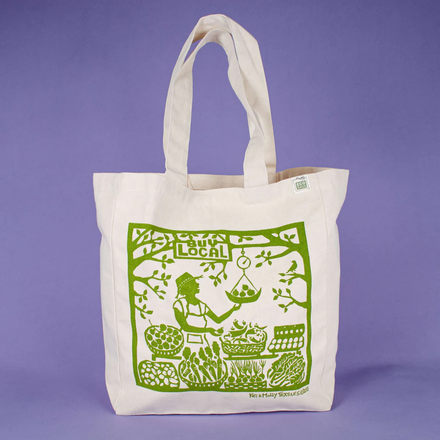 White tote bag with green screen print on a purple background