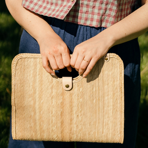 Person holding a woven clutch bag outdoors