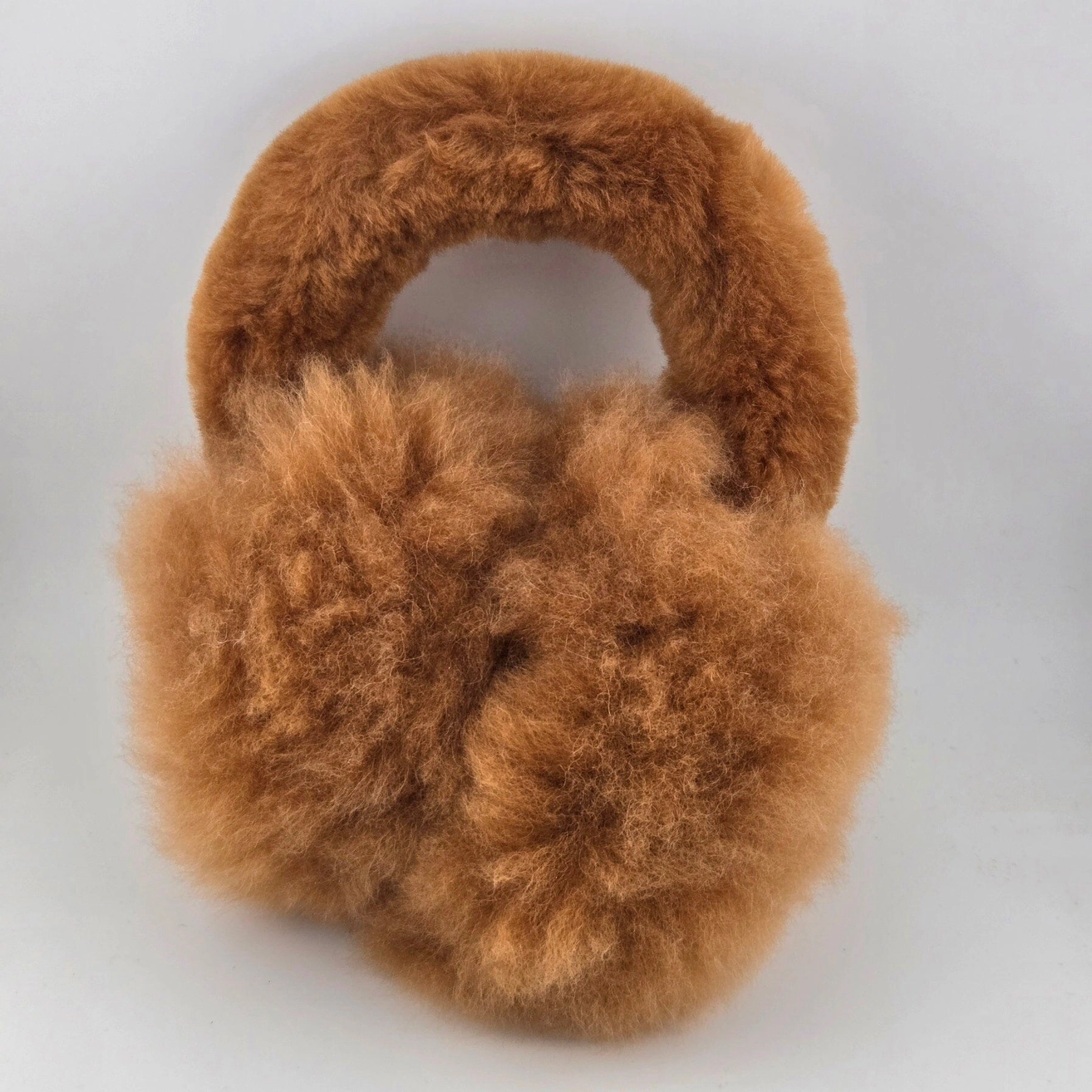 Fluffy alpaca fur winter ear muffs in brown, shown on a plain light gray background.