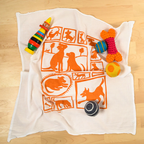 Dog toys on a white towel with orange dog illustrations on a wooden surface