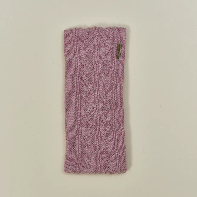 Pink knitted headband with cable pattern on a beige background