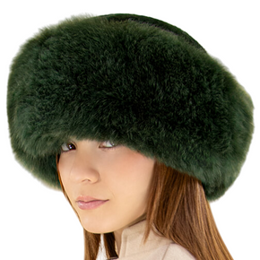 Person wearing a green fur hat with a beige background, featuring the Classic Alpaca brand.