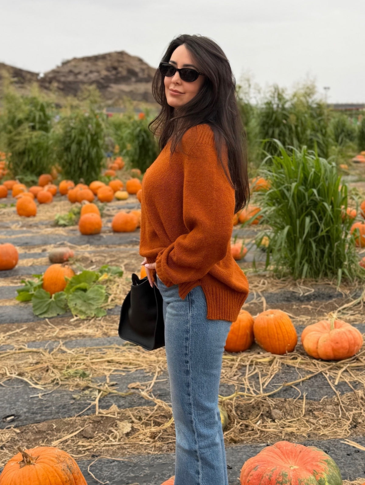 Emma wearing the Monterey alpaca V-neck sweater in pumpkin at a pumpkin patch