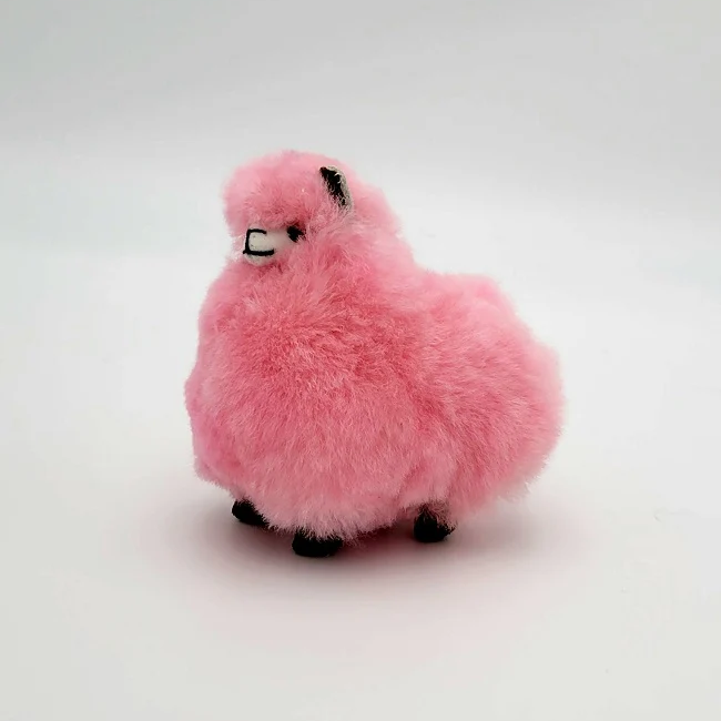 A plush pink alpaca keychain on a neutral background.