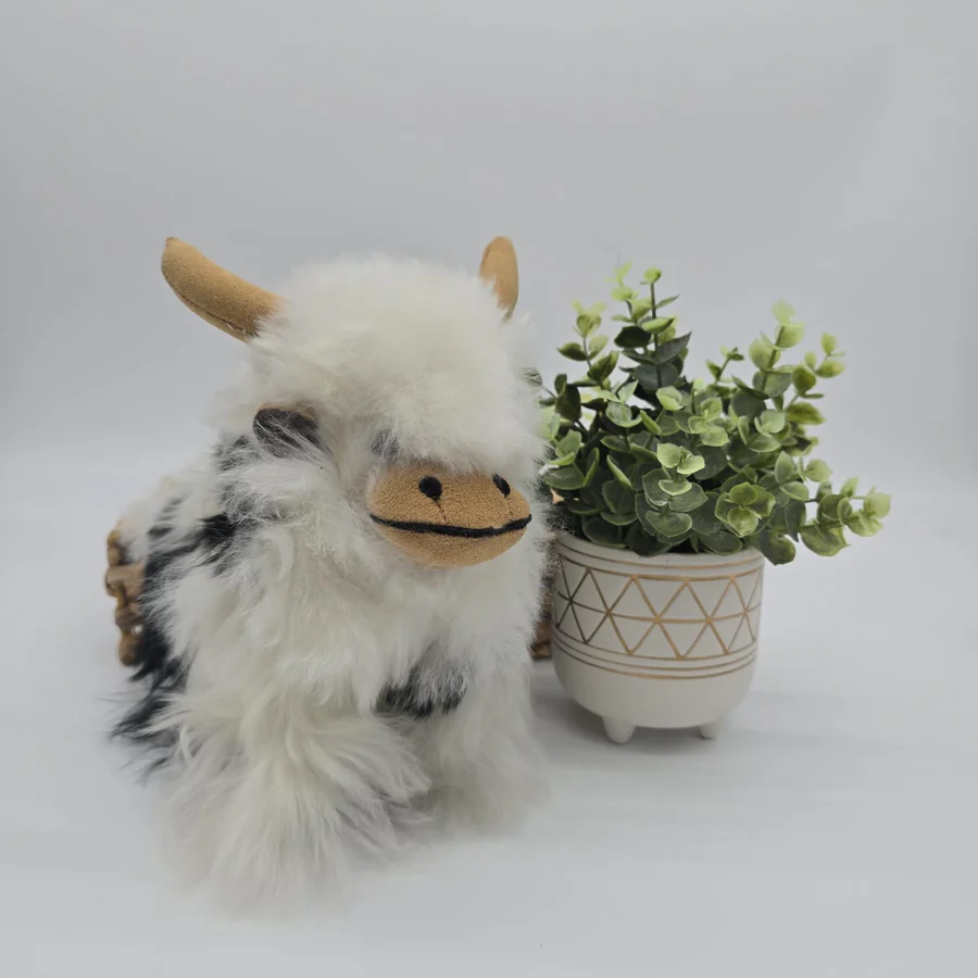 Plush toy yak next to a small potted plant on a light gray background