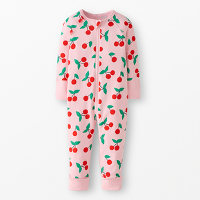 Pink zip up baby onesie with a cherry print on a neutral background.