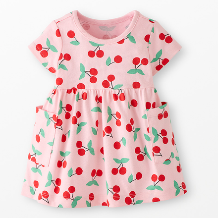 A pink dress with a red cherry pattern in a neutral background.