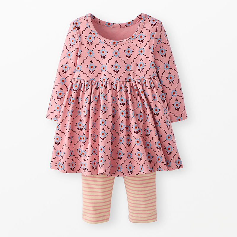 Children's pink floral long-sleeved dress over pink and white striped leggings on a neutral background.
