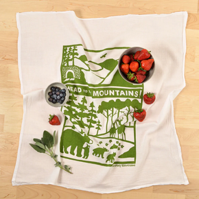 White towel with green nature-themed design and strawberries on a wooden surface