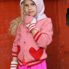 Cabbages and Kings Nuevo Heart Cardigan - girl wearing a pink cardigan with red heart pockets and red stripes on a red background