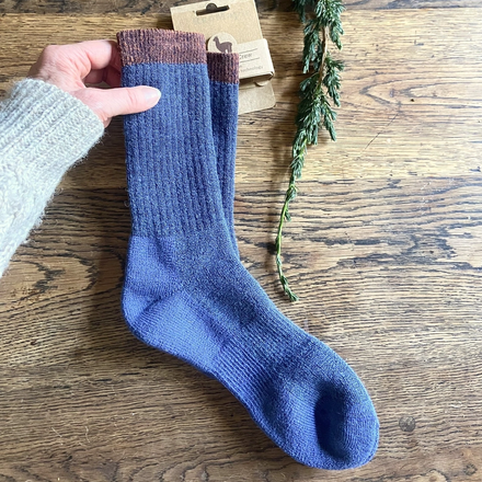 Blue socks with brown top held by a hand on a wooden surface