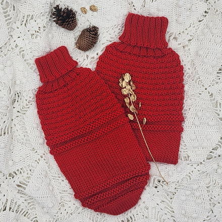 Red textured knit dog sweaters against a white surface