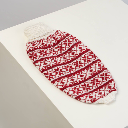 Red and white patterned knitted dog sweater on a white surface
