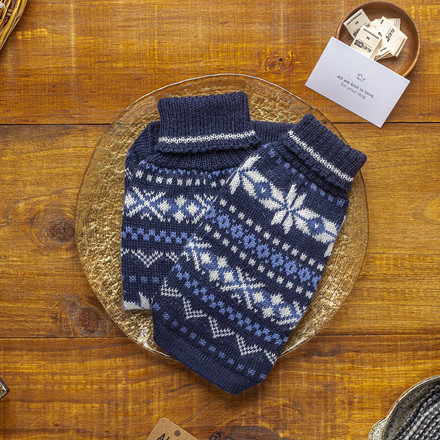 Blue knitted dog sweater with white patterns on a wooden surface