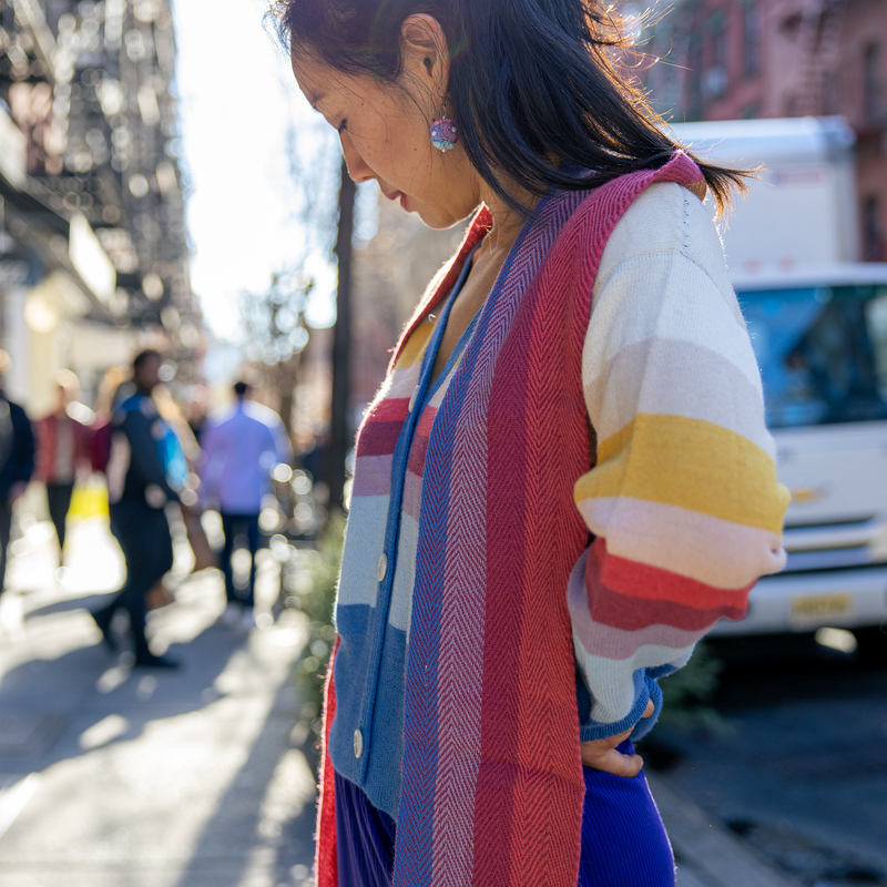 Woman wearing a colorful scarf and striped sweater on a city street.