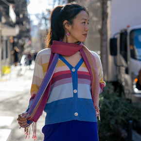 Woman wearing a colorful striped sweater and blue pants on a city street.