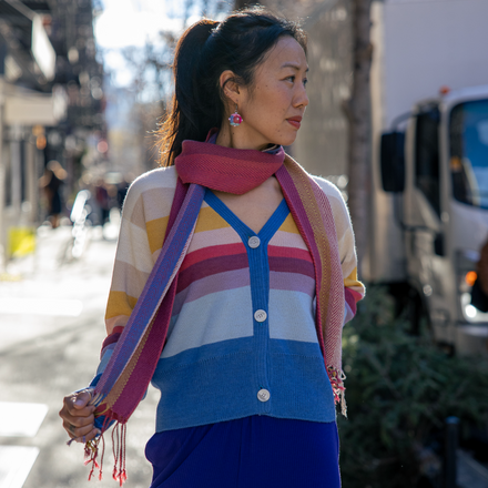 Woman wearing a colorful striped sweater and blue pants on a city street.